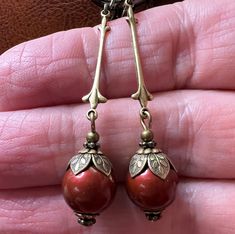 Simple vintage inspired earrings with 10mm Swarovski Bordeaux/Wine colored Crystal Pearls. The earrings are accented with antiqued brass bead caps. They are approximately 2.5 inches long and come in a gift box. Vintage Red Brass Earrings, Red Brass Earrings With Ear Wire, Vintage Red Clip-on Earrings As Gift, Unique Red Earrings For Formal Events, Unique Red Earrings For Formal Occasions, Vintage Red Drop Clip-on Earrings, Red Vintage Style Drop Clip-on Earrings, Red Brass Drop Earrings, Vintage Red Single Earring