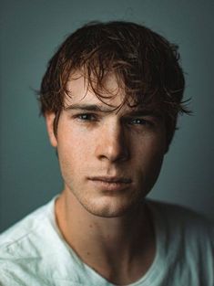 a close up of a person wearing a white t - shirt and looking at the camera