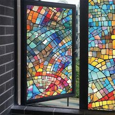 two colorful stained glass windows on the side of a building with an open door in front of them