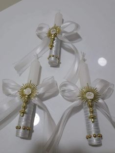 three white and gold christmas ornaments with ribbons