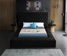 a black bed with blue and white pillows in a modern style bedroom, along with two side tables