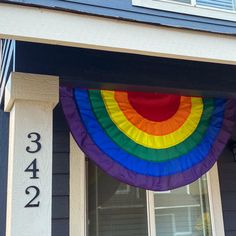 there is a large rainbow flag hanging from the side of a house with numbers on it