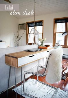 a desk with a laptop on it in a room that has windows and wood flooring