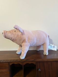 a stuffed pig sitting on top of a wooden dresser