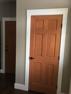 an empty room with a wooden door and hard wood floors