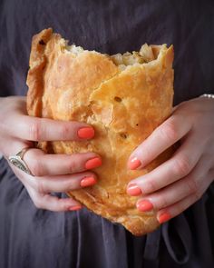 a woman is holding a large pastry in her hands with orange nail polish on it