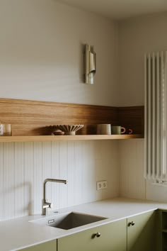 a kitchen with green cabinets and white counter tops, along with a stainless steel sink