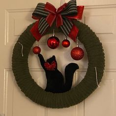 a wreath with ornaments and a cat hanging on the front door to give it a festive touch