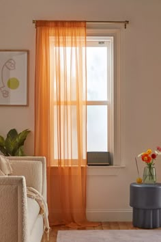 a living room filled with furniture and a window covered in yellow draping next to a white rug