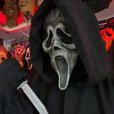 a person in a black hoodie with a large knife sticking out of it's mouth