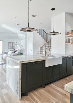 an open kitchen with marble counter tops and black cabinets, along with stairs leading up to the second floor