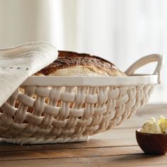 a loaf of bread sitting in a basket next to a bowl with butter on it