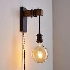 an old fashioned light bulb is hanging from the wall next to a small lamp fixture