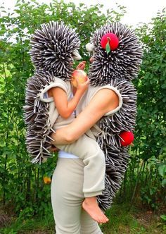 a woman holding a child in her arms made out of fake hedgehogs and flowers