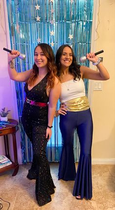 two women standing next to each other in front of a blue curtain with lights on it