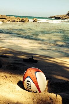 an orange and white ball sitting on top of a sandy beach next to the ocean