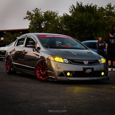 a gray car with red rims parked in a parking lot