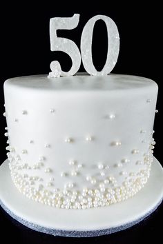 a white cake with pearls and the number 50 on it's top is shown