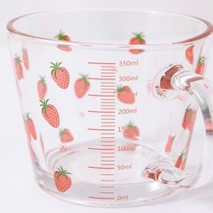 a measuring cup with strawberries printed on the front and sides, sitting on a white surface