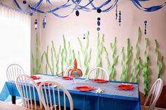 the table is set with blue and green paper streamers hanging from it's ceiling