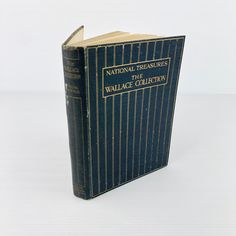 an old book sitting on top of a white table next to a black and gold cover