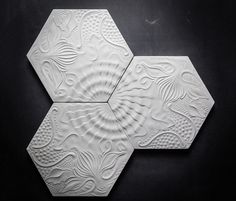 three white hexagonal tiles with intricate designs on the surface, arranged in a spiral pattern