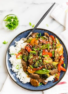 a blue plate topped with stir fry beef and veggies