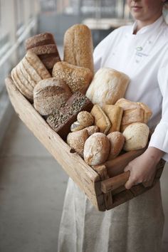 a woman holding a basket full of bread