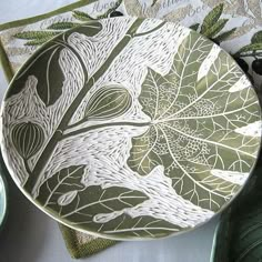 a green plate with white designs on it next to other plates and napkins sitting on a table