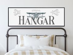 a bed with a white comforter and a framed sign above it