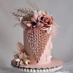 a pink cake decorated with flowers and feathers