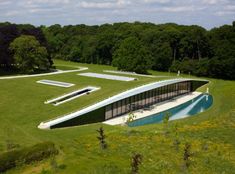 an aerial view of a pool surrounded by green grass and lots of trees in the background