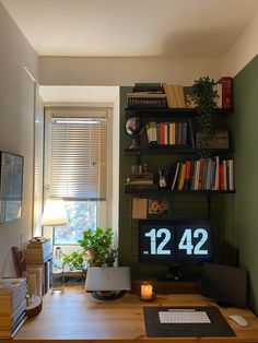 a desk with a computer monitor and keyboard on it in front of a book shelf