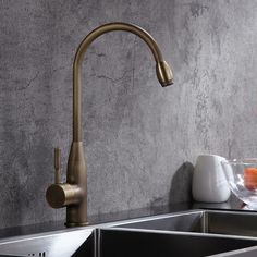 a kitchen sink with a faucet next to a bowl of fruit on the counter