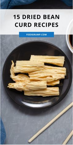 some food is on a black plate with chopsticks