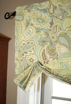 a window with a green and blue curtain hanging from it's valance next to a bed