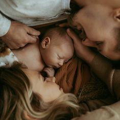 a man and woman laying on top of a bed next to a baby sleeping in their arms