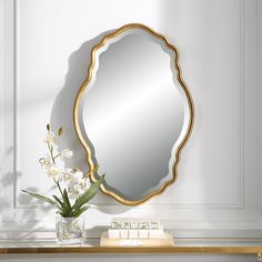 a mirror sitting on top of a table next to a vase with flowers