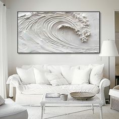 a living room with white furniture and a large painting on the wall above the couch