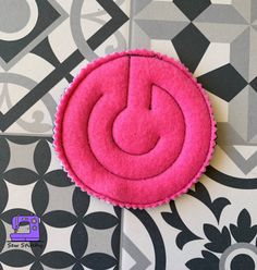 a pink circular object sitting on top of a tiled floor