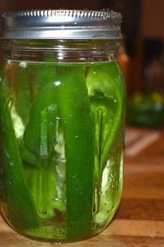 pickled cucumbers in a mason jar sitting on a counter top, ready to be cooked