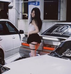 a woman standing next to some parked cars