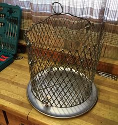 a birdcage sitting on top of a wooden table next to a green tool box