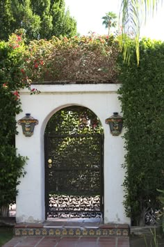 an archway is surrounded by greenery and potted plants