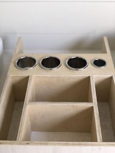 an open drawer with three bowls in it on a table next to a cup holder