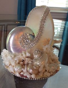 a fancy cake with pearls and seashells on it's side, sitting on a table