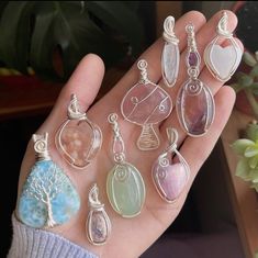 a person holding seven different pendants in their palm, with one being held up to the camera