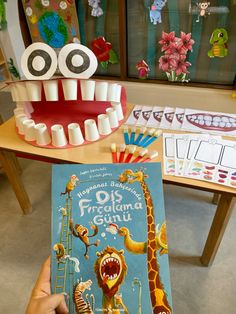 a person holding up a book in front of a fake toothbrush and an open mouth