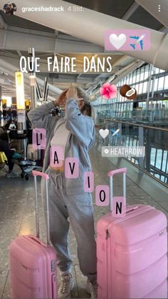 a woman standing next to two pink suitcases in an airport with words written on them