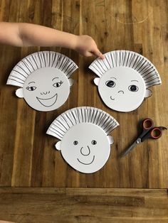 three paper plates with hedgehog faces cut out on a wooden table next to scissors